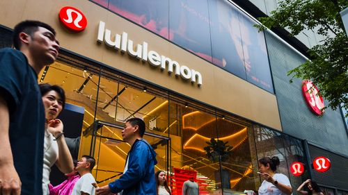 I pedoni passano davanti a un negozio al dettaglio Lululemon con la segnaletica del marchio e gli espositori interni visibili attraverso grandi vetrate.