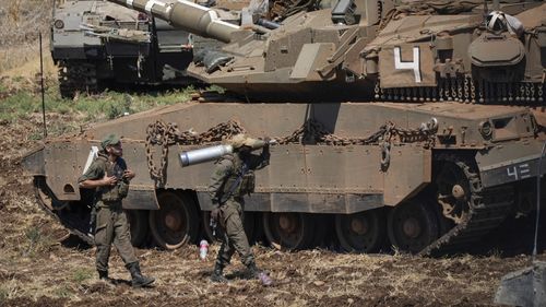 An Israeli soldier carries a shell next to a tank in northern Israel on Friday, September 27.