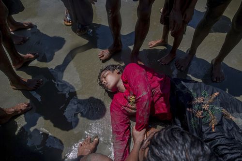 A Rohingya Muslim woman, who crossed over from Myanmar into Bangladesh, lies unconscious on the shore of the Bay of Bangal after the boat she was travelling in capsized. (AP)