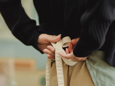 Stock image of a waitress tying an apron.