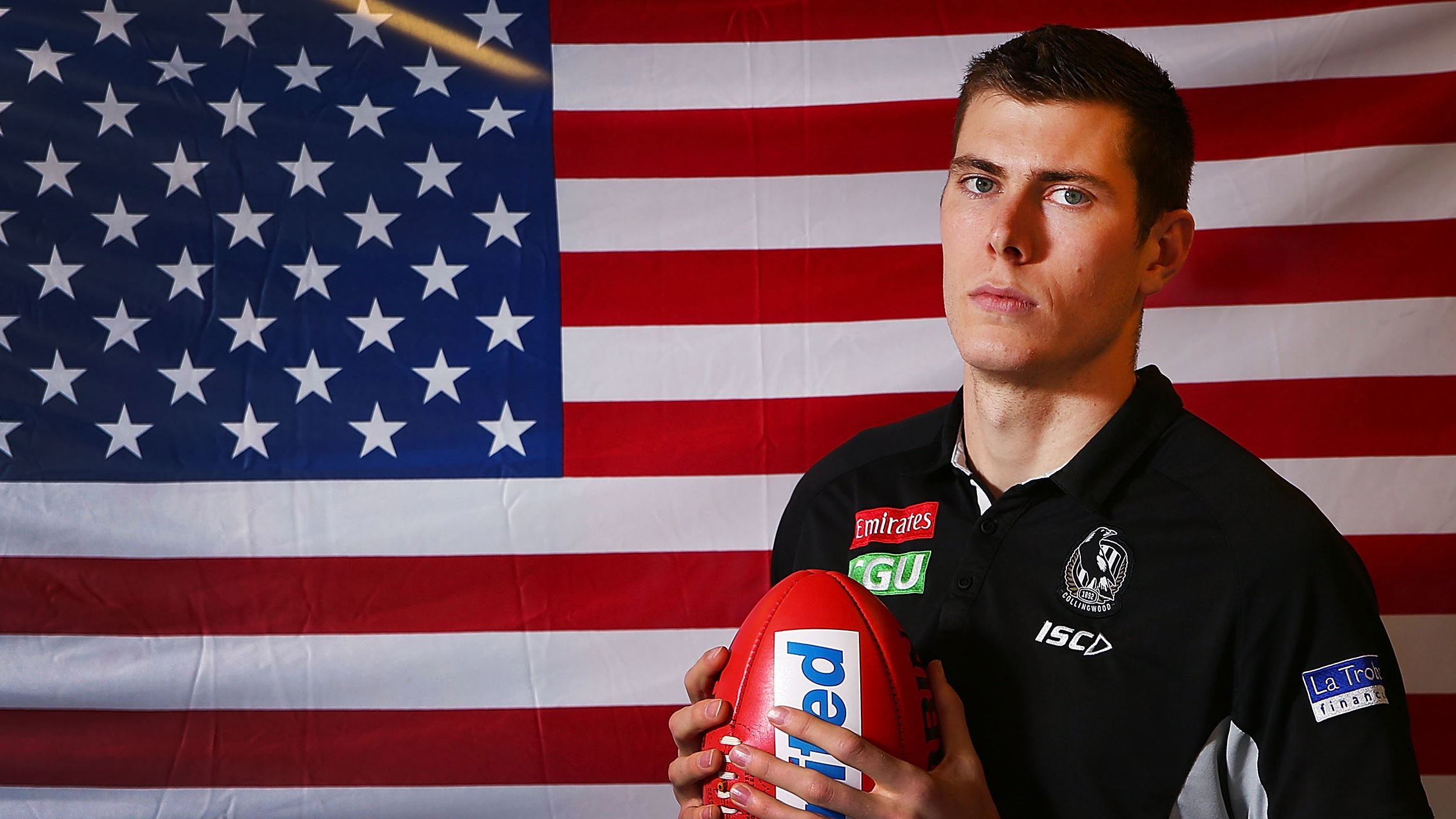 Mason Cox, the first American to play in the AFL, poses in front of his national flag.
