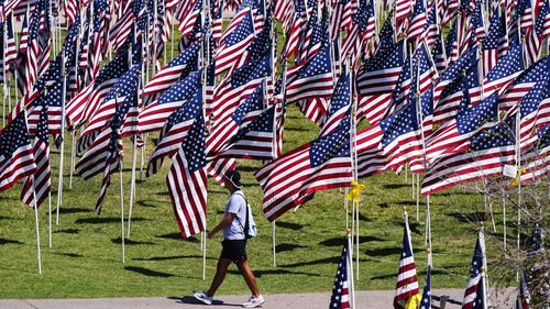 A pedestrian walks past a field of American flags, each representing every victim murdered in the terrorist attacks of Sept. 11, 2001, at the 9/11 Memorial Healing Field, in Tempe, Arizona.