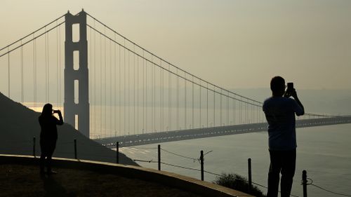 People take pictures of the Golden Gate Bridge as smoke from wildfires covers the San Francisco skyline. (AP)