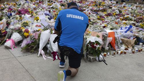 A surf lifesaver places flowers at the memorial for the Bondi Beach shootings in front of the Bondi Beach Pavillion, Bondi Beach, Sydney, 16 December 2025.. Photo: Jessica Hromas