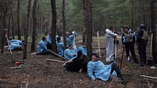 Emergency workers have a rest during the exhumation of bodies in the recently retaken area of Izium, Ukraine, Friday, Sept. 16, 2022. 