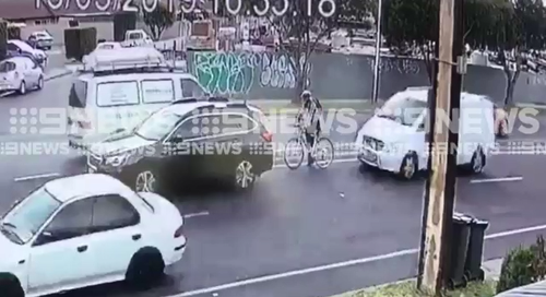 As the cyclist pulled to a stop behind another car at the lights, a white approached behind the rider. 