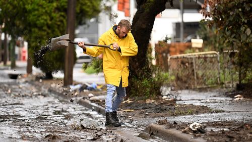 Eli Roth clears mud and debris from a drain outside his house in Lismore, NSW.