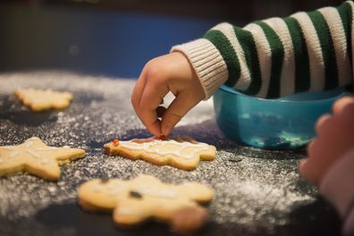 A child decorated Christmas biscuits.
