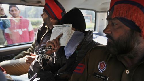 Puneet covers his face as he is escorted by police. (Image: AAP)