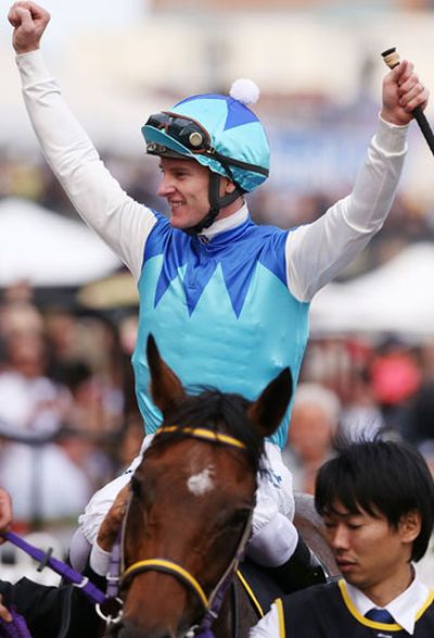 Zac Purton raises his arms in triumph after Admire Racti's Caulfield Cup win.