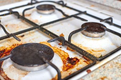 Dirty grease stove with food leftovers. Unclean gas kitchen cooktop with greasy spots, old fat stains, fry spots and oil splatters.