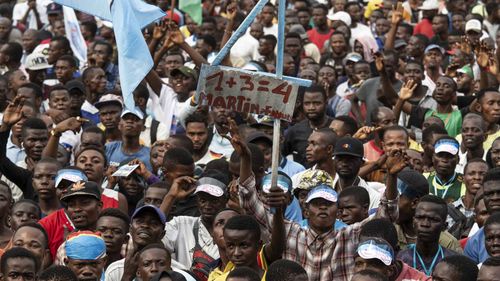 A supporter of the opposition's presidential candidate Martin Fayulu holds up a placard reading '1+3=4, which referrs to Fayulu's number on the candidates' list.