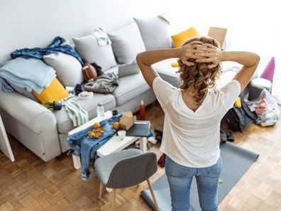 Woman looking at her messy loungeroom, cleaning