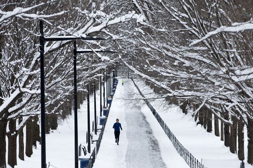 A jogger runs on a snow-covered path near the Lincoln Memorial Reflecting Pool in Washington.