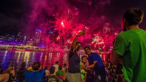 People are watching fireworks ahead of New Year’s Eve across the Brisbane River at the Southbank in Brisbane last year.