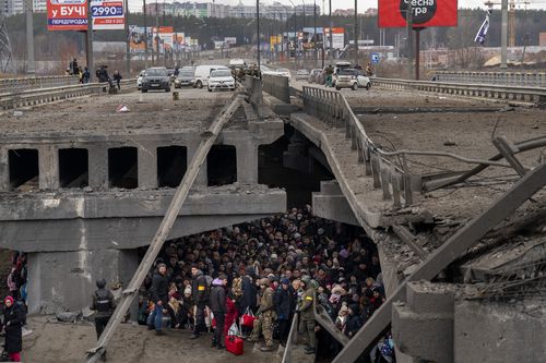 Ukrainians crowd under a destroyed bridge as they try to flee crossing the Irpin river in the outskirts of Kyiv, Ukraine, Saturday, March 5, 2022.  