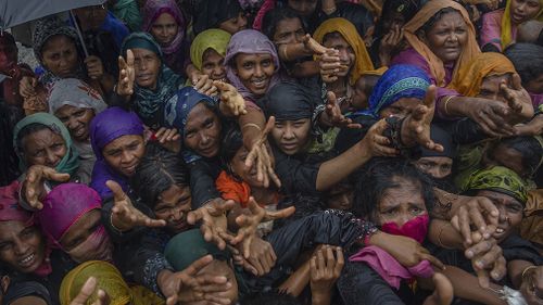 Rohingya Muslim women in Bangladesh stretching out their arms to collect sanitary products distributed by aid agencies. (AAP)