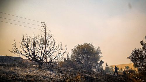 People try to extinguish a wildfire on the island of Rhodes, Greece, July 22, 2023. 