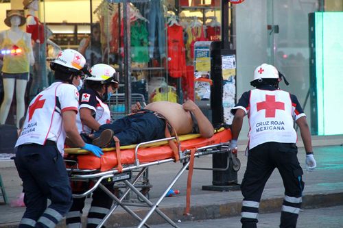 Paramedics rush one of the wounded to hospital in Cancun last Wednesday, following a drive-by shooting at a food stand which left three people dead. (AAP)