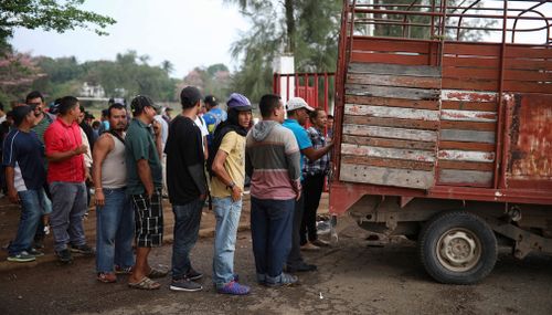 Central American migrants wait in line to receive food. (AP)