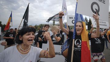 Romanian supporters of QAnon shout slogans against the government&#x27;s measures to prevent the spread of COVID-19 infections.
