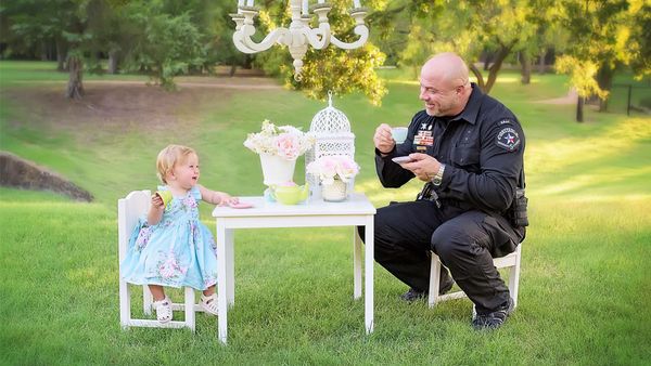 Tea for two: Evelyn Hall celebrates her first birthday with Officer Diebold who delivered her by the roadside. Image: Cyndi Williams Photography