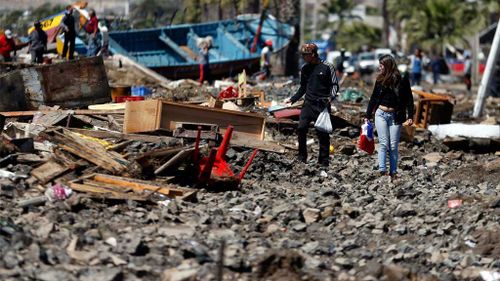 People walk through the debris. (AAP)