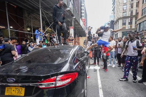 A person jumps on the top of a car as kicks in the window near Union Square park, Friday, Aug. 4, 2023, in New York. 