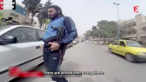 Men are seen carrying assault rifles throughout the city. (France 2)