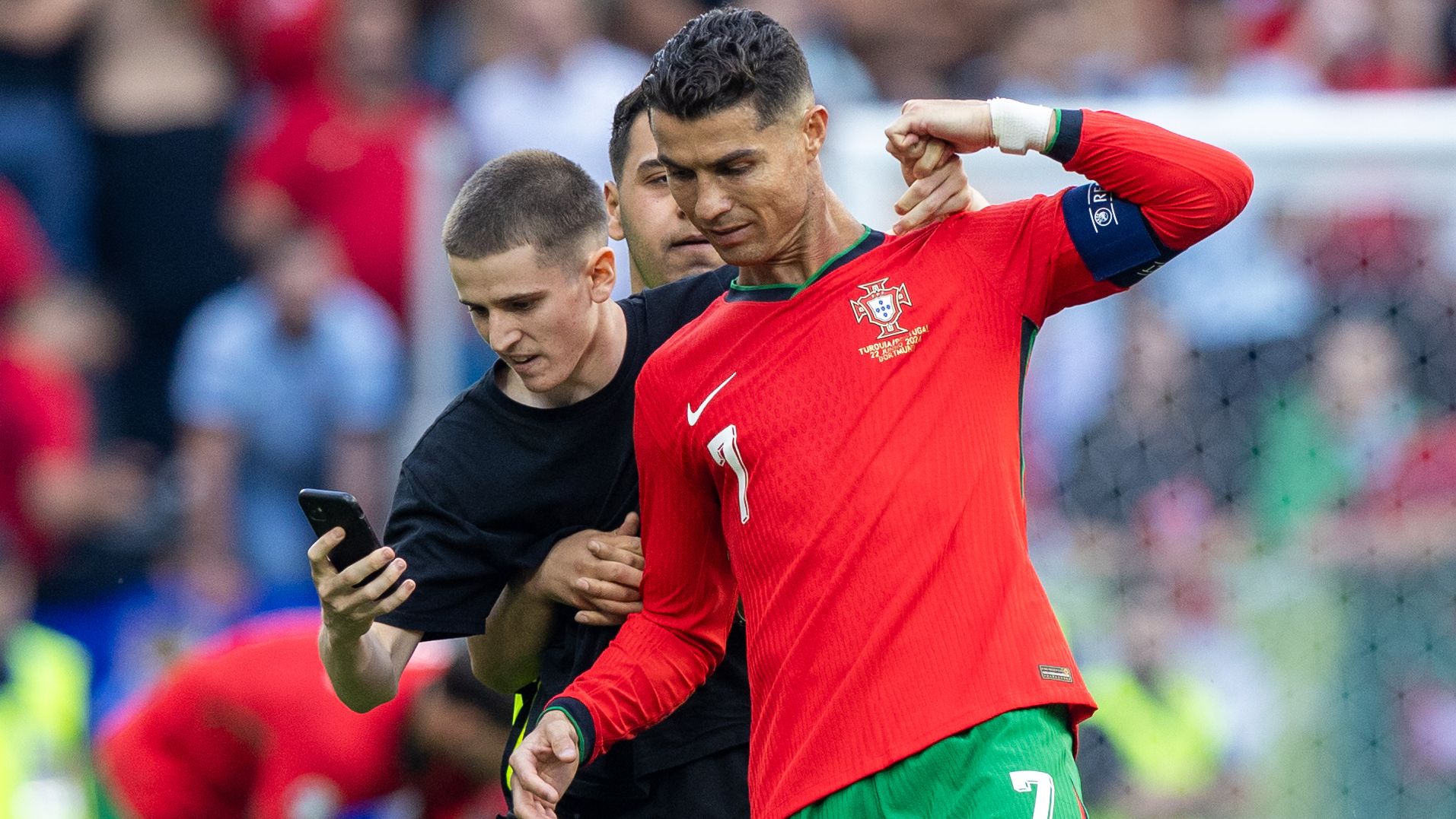 A pitch invader takes a selfie photograph with Portugal forward Cristiano Ronaldo during the UEFA Euro 2024 Group F match between Turkiye v Portugal, at the  BVB Stadion Dortmund in Dortmund, Germany, on June 22, 2024. (Photo by Andrzej Iwanczuk/NurPhoto via Getty Images)