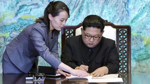 North Korean leader Kim Jong Un signs a joint declaration, with the help of his sister Kim Yo Jong (L), a senior official of the ruling Workers' Party, after talks with South Korean President Moon Jae In at the House of Peace in the border village of Panmunjeom on April 27, 2018. 