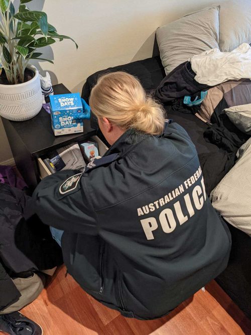 An AFP officer searches through the bedside drawers of a Willoughby man.