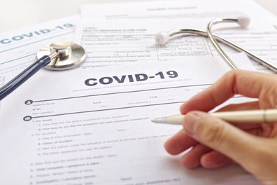 COVID-19 Health insurance concept. Blurring of hand holding pen and Stethoscope on health form. Focus on " COVID-19 "