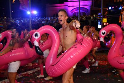 Men march while wearing pink flamingo pool toys. (AAP)