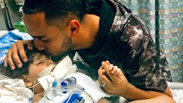 Ali Hassan kissing his dying 2-year-old son Abdullah in a Sacramento hospital. The boy's Yemeni mother, blocked by the Trump administration's travel ban, has won her fight for a waiver that would allow her to travel to California to see her son. 