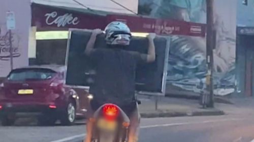 Two men on a scooter have been filmed hauling what appears to be a television in Sydney's Inner West.