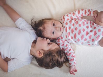 Baby and toddler sister laying down together