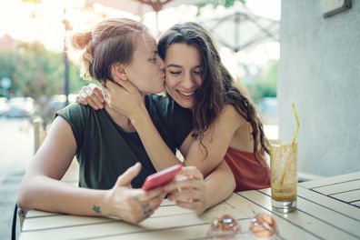 Young couple, two women, embracing and drinking iced coffee
