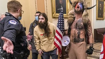 In this Wednesday, January 6, 2021 file photo, supporters of President Donald Trump, including Jacob Chansley,  with fur hat, are confronted by Capitol Police officers outside the Senate Chamber.