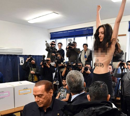 Silvio Berlusconi leaves after being confronted by a protester at an Italian election polling station on Sunday, March 4. (AAP)