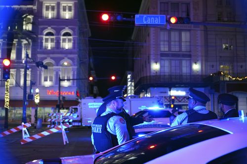 Police officers stand near the scene where a vehicle drove into a crowd on New Orleans' Canal and Bourbon streets