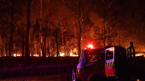 A RFS fire fighter with the Charmhaven unit monitors a small flare up on New Years Day on the Kings Highway near Batemans Bay.