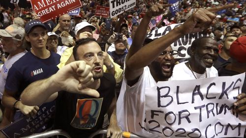 A man wearing a QAnon shirt jeers at a CNN reporter at a Donald Trump rally.