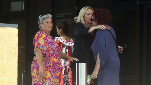 Mourners embrace outside a memorial for the victims of the Cairns child massacre victims. (AAP)