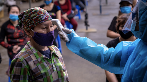 HANOI, VIETNAM - APRIL 18: A medical worker in protective suit takes temperature of a labourer from Long Bien market before taking the coronavirus disease (COVID-19) rapid test on April 18, 2020 in Hanoi, Vietnam. 