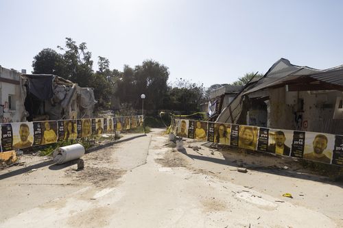 Placards with photos of hostages held in the Gaza Strip after the October 7 Hamas attack hang on damaged houses on April 7, 2024 in Kfar Aza, Israel. April 7th marks six months since Hamas led an attack on Israel, killing 1,200 people and taking around 250 people hostage.