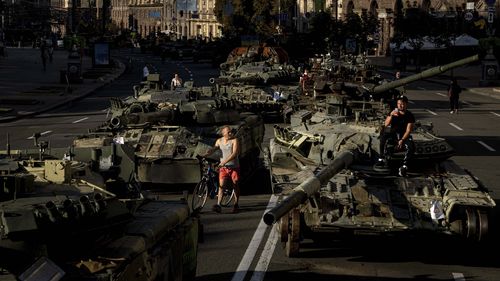 La gente camina alrededor de vehículos militares rusos destruidos instalados en el centro de Kyiv, Ucrania, el miércoles 24 de agosto de 2022. Las autoridades de Kyiv prohibieron las reuniones masivas en la capital hasta el jueves por temor a los ataques con misiles rusos.  El Día de la Independencia, como la marca de seis meses en la guerra, cae en miércoles.  (Foto AP/Evgeniy Maloletka)