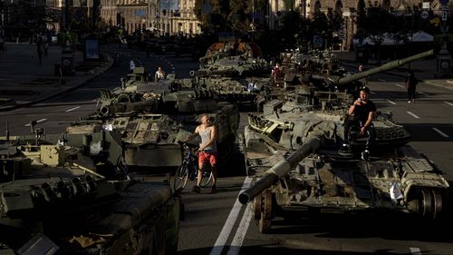 People walk around destroyed Russian military vehicles installed in downtown Kyiv, Ukraine, Wednesday, Aug. 24, 2022. Kyiv authorities have banned mass gatherings in the capital through Thursday for fear of Russian missile attacks. Independence Day, like the six-month mark in the war, falls on Wednesday. (AP Photo/Evgeniy Maloletka)