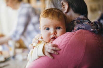 Grandmother holding her newborn baby Granddaughter over her shoulder.