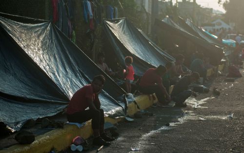 Honduran migrants start their day under improvised tents along a bridge that stretches over the Suchiate River, connecting Guatemala with Mexico.